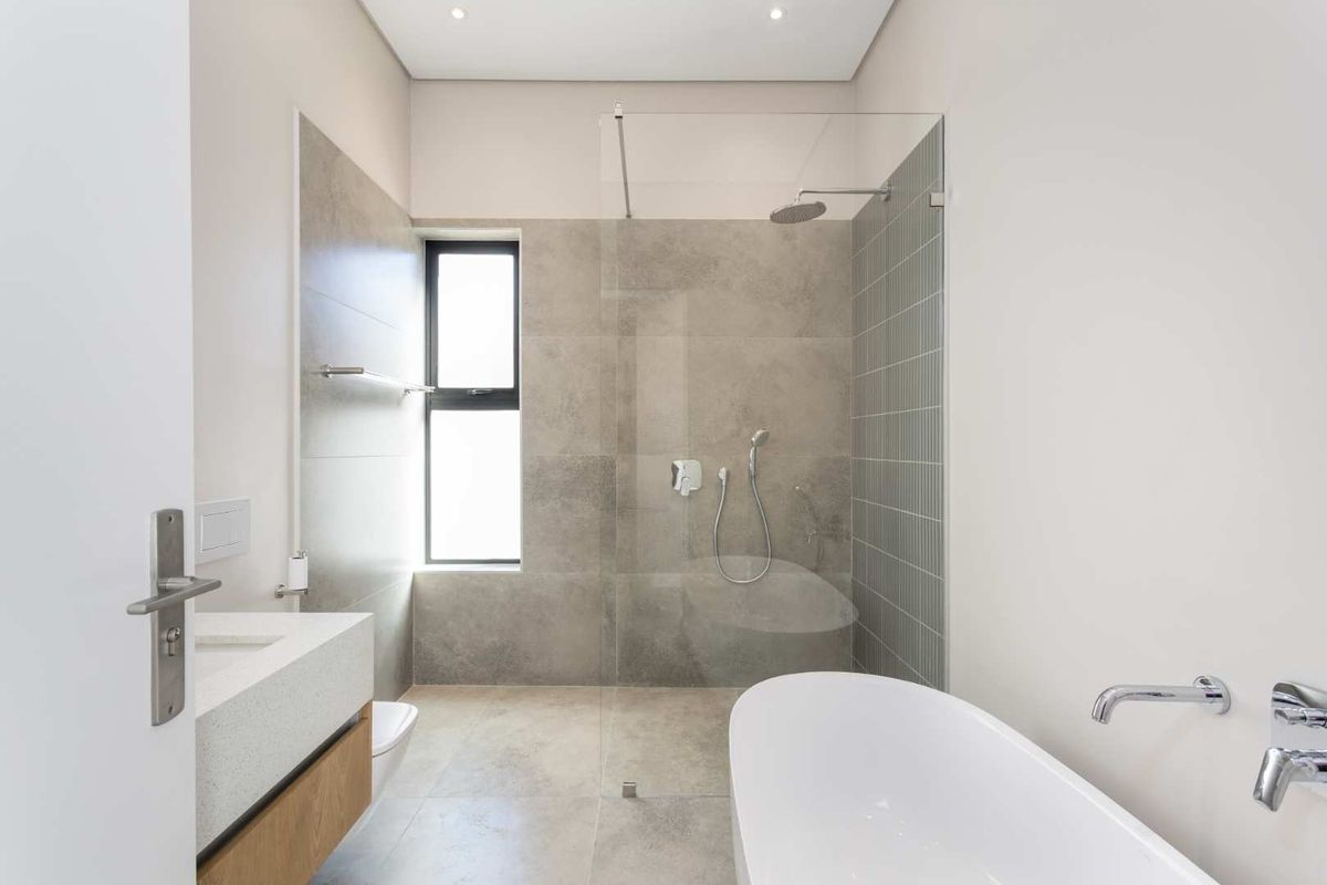Modern, well-appointed bathroom featuring a sleek freestanding bathtub, a spacious walk-in shower with glass enclosure, and a contemporary wall-mounted vanity.