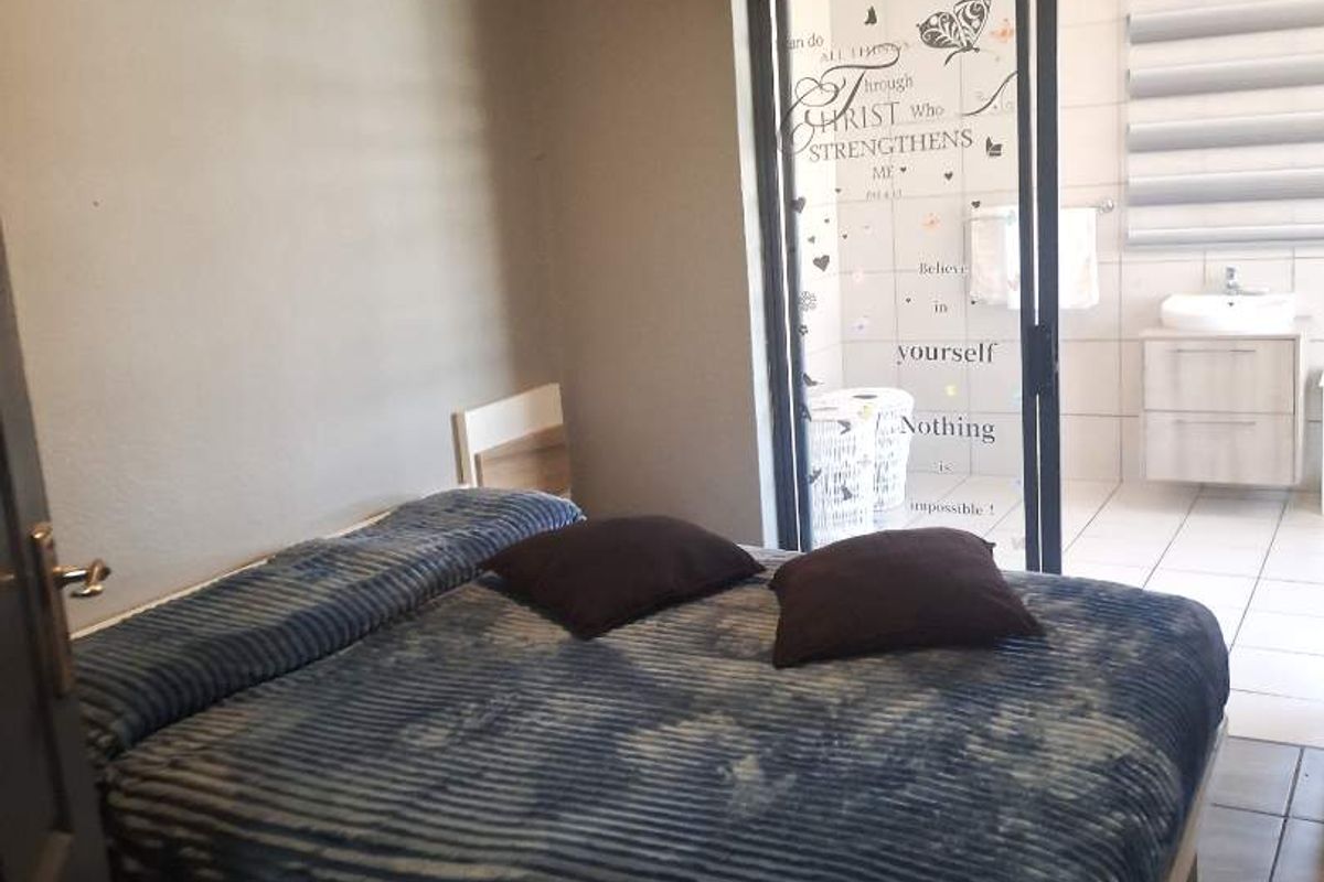 A bedroom featuring tiled flooring and a sliding glass door providing direct access to an en-suite bathroom.