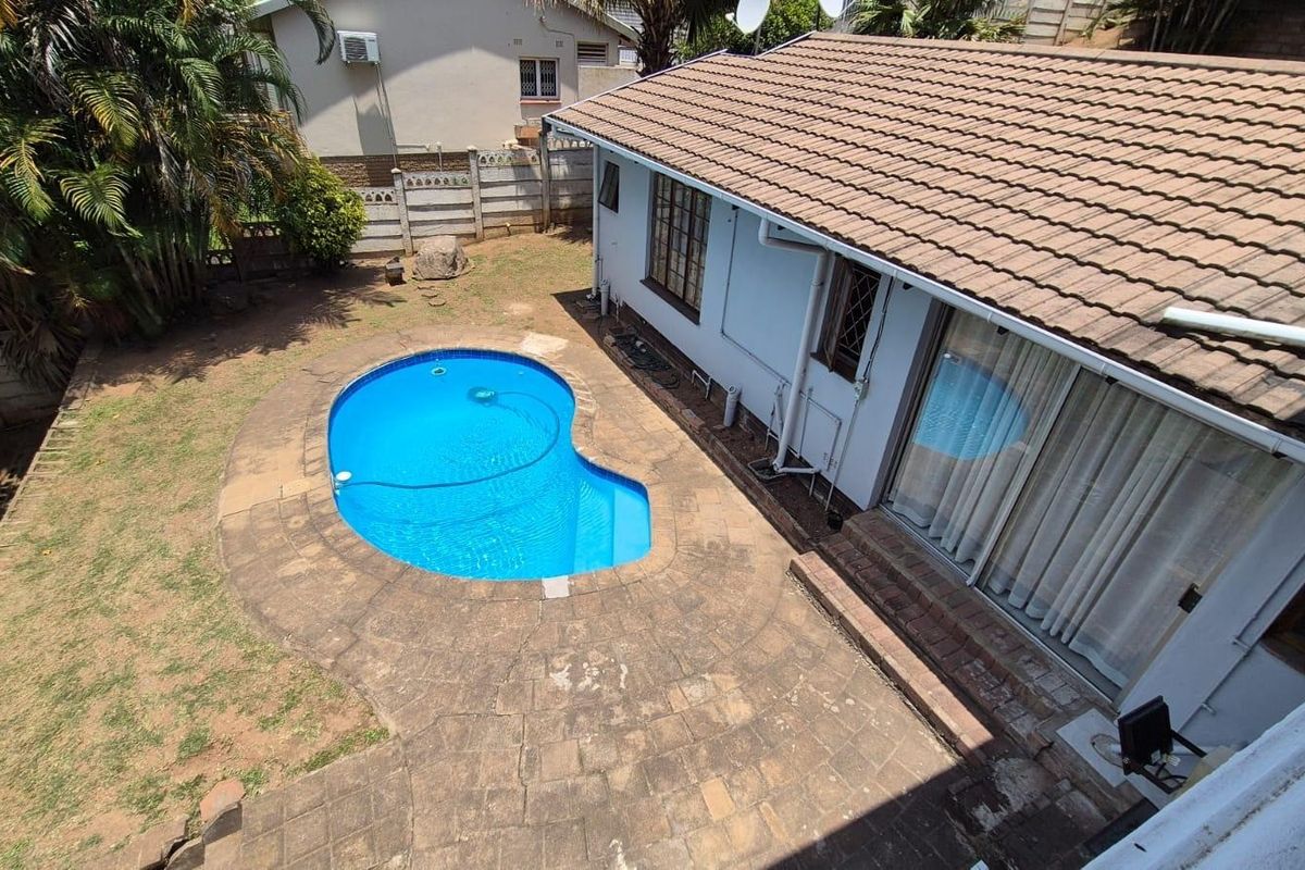 Rear exterior view featuring a swimming pool, paved patio area, and direct access to the home via sliding glass doors.