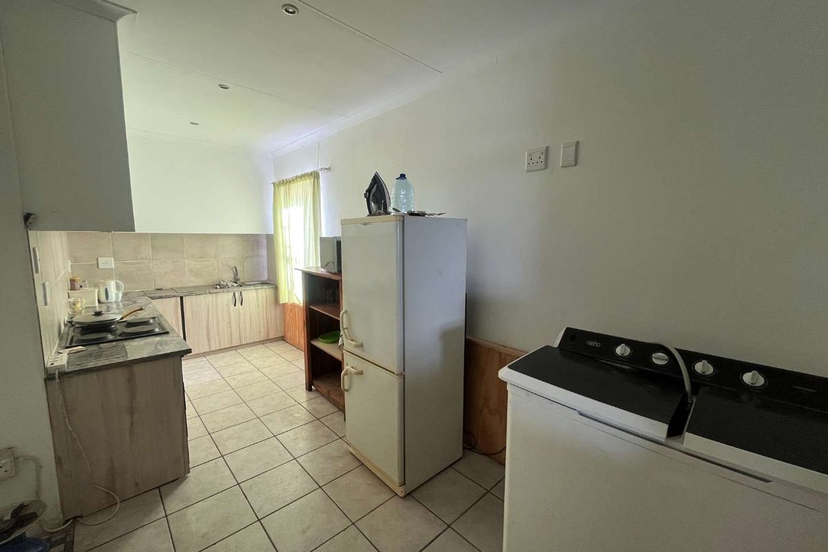 Functional kitchen area featuring tiled flooring, built-in cabinetry, integrated hob, and dedicated space for laundry appliances.