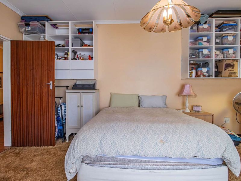 A bedroom featuring built-in shelving units, carpet flooring, and a central ceiling light fixture.