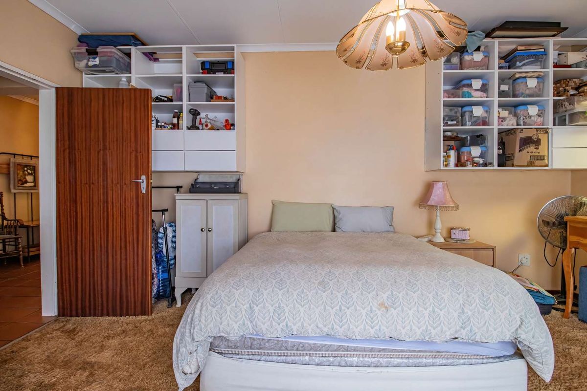A bedroom featuring built-in shelving units, carpet flooring, and a central ceiling light fixture.