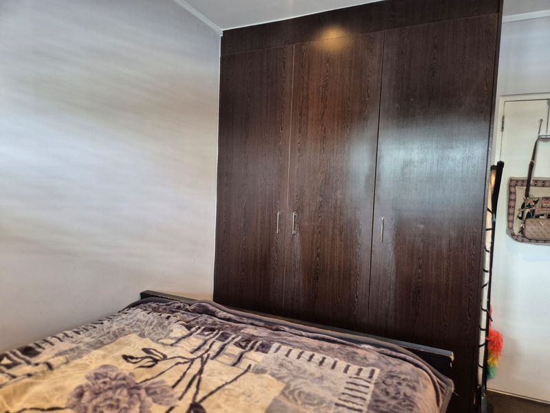 A bedroom featuring a large, dark wood-finish built-in wardrobe providing ample storage space.