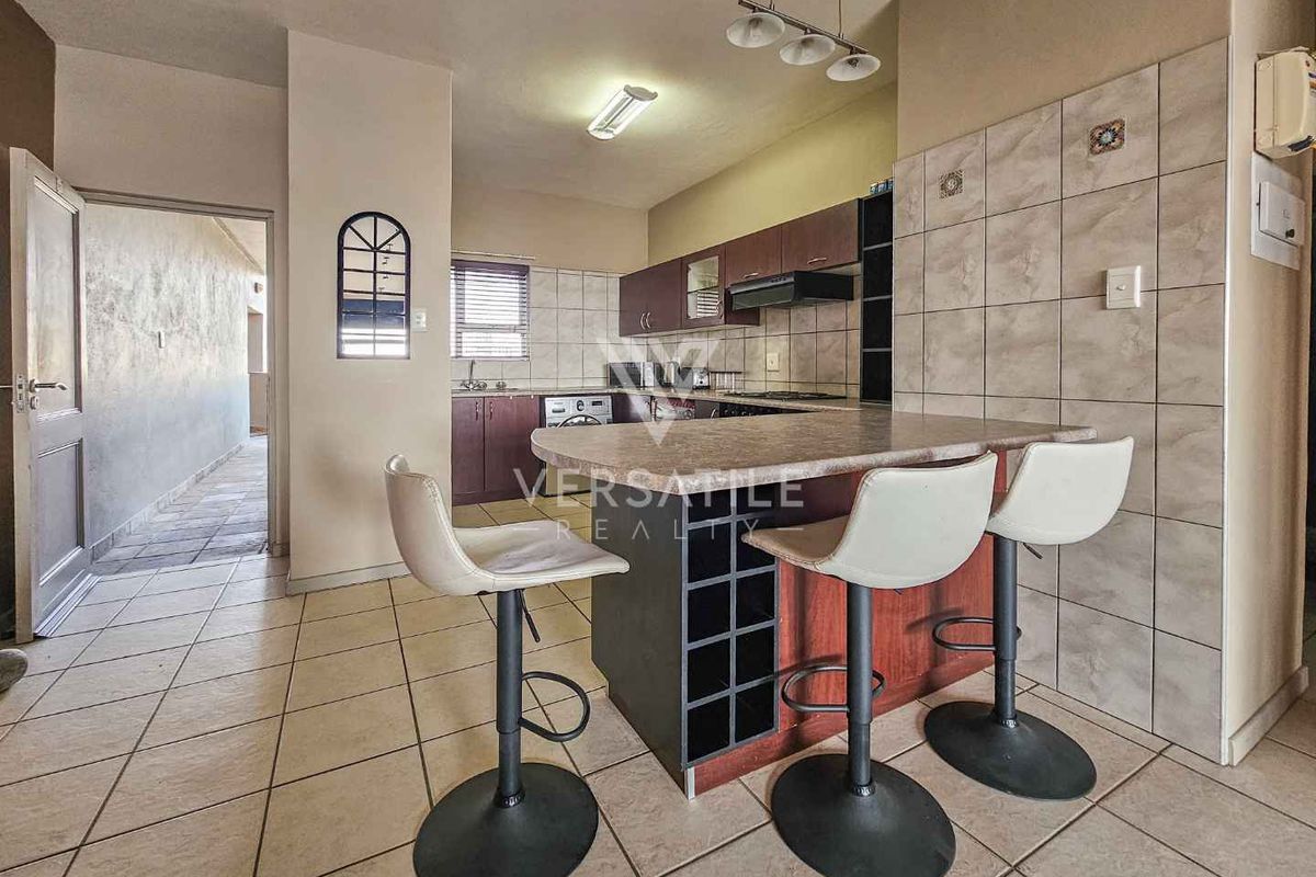 A functional kitchen featuring a breakfast bar, built-in cabinetry, tiled backsplash, and integrated hob, providing a practical layout for daily meal preparation.