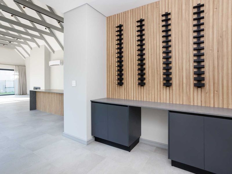 Modern open-plan living area featuring timber slat wall paneling, built-in cabinetry with stone countertops, exposed rafters, and large sliding doors leading to the exterior.