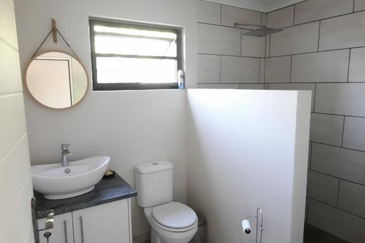 Modern bathroom featuring a vessel sink vanity, a walk-in shower with rain shower head, and polished concrete flooring.