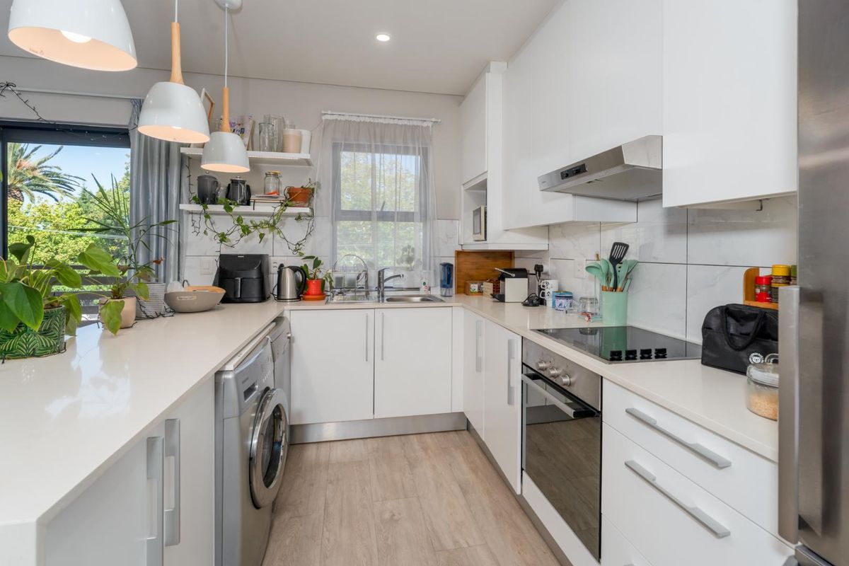 Modern kitchen featuring white cabinetry, stone countertops, integrated appliances, and a tiled backsplash, with direct access to an outdoor balcony area.