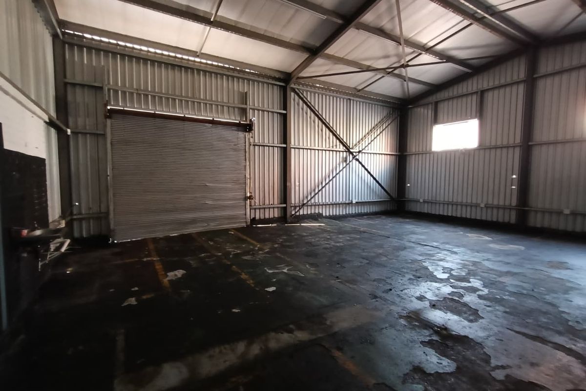 Spacious industrial utility area featuring a high-clearance steel frame structure, corrugated metal walls, and a large roller shutter door for vehicle or equipment access.
