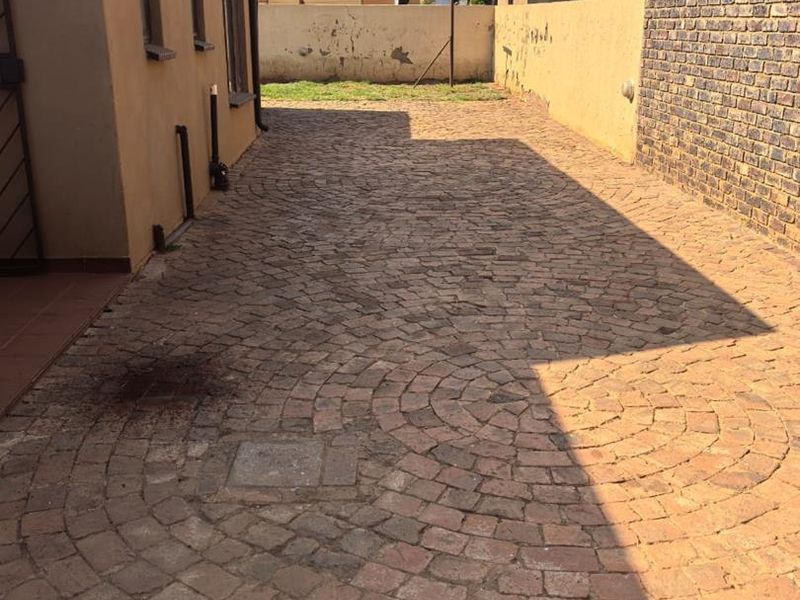 A rear exterior area featuring cobblestone paving and a boundary wall with visible wear, offering potential for landscaping or outdoor improvement.