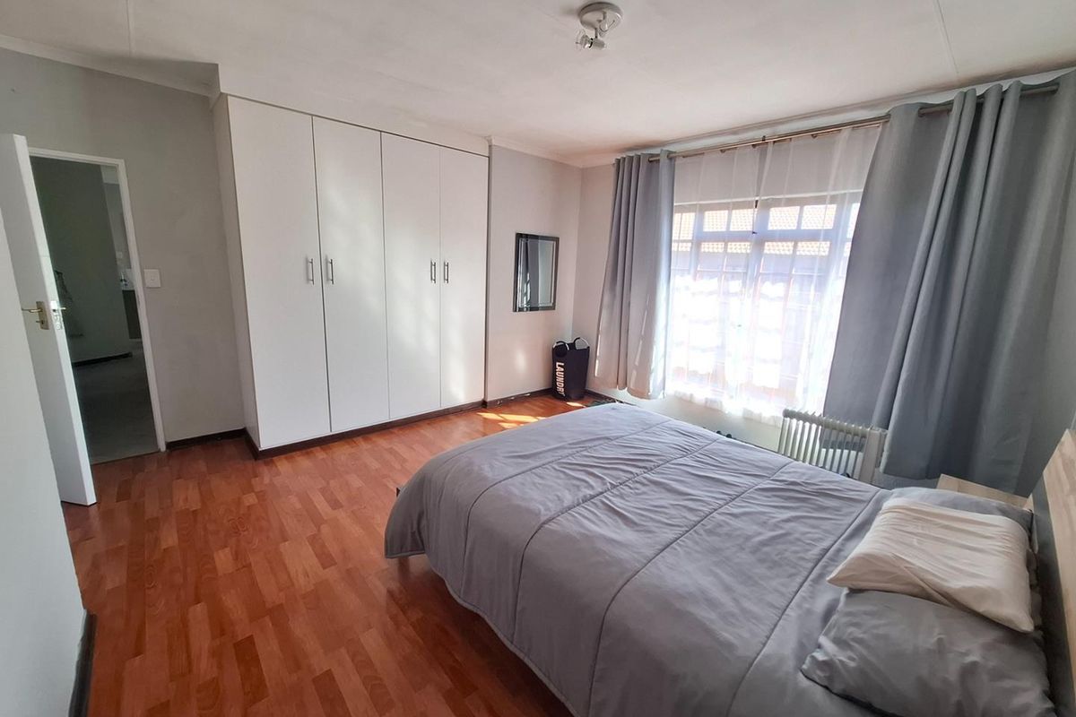 A well-lit bedroom featuring laminate flooring and ample built-in cupboard storage space.