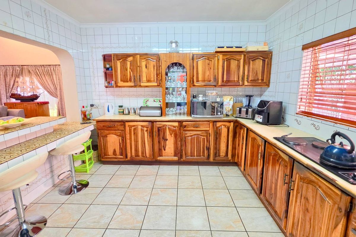 A functional kitchen featuring wooden cabinetry, tiled backsplash, and a breakfast bar, offering a traditional layout with ample storage and counter space.