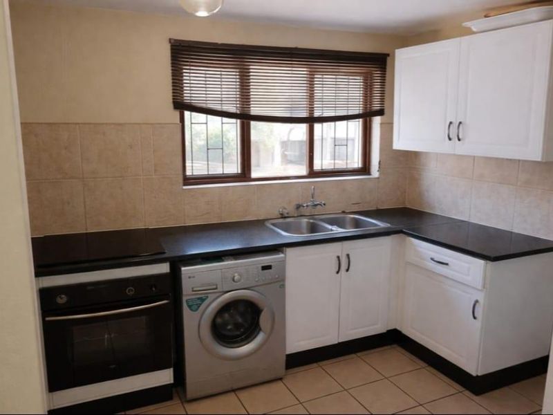 A functional kitchen featuring white cabinetry, dark countertops, a built-in oven with hob, and tiled backsplash, offering a clean and practical workspace.
