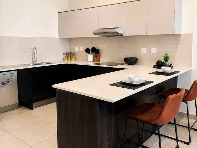 Modern kitchen featuring dark wood cabinetry, light stone countertops, integrated appliances, and a breakfast bar island with tiled flooring.