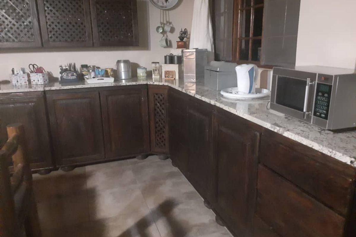 A rustic kitchen featuring dark wood cabinetry, granite countertops, and tiled flooring, providing a functional prep space with integrated storage.
