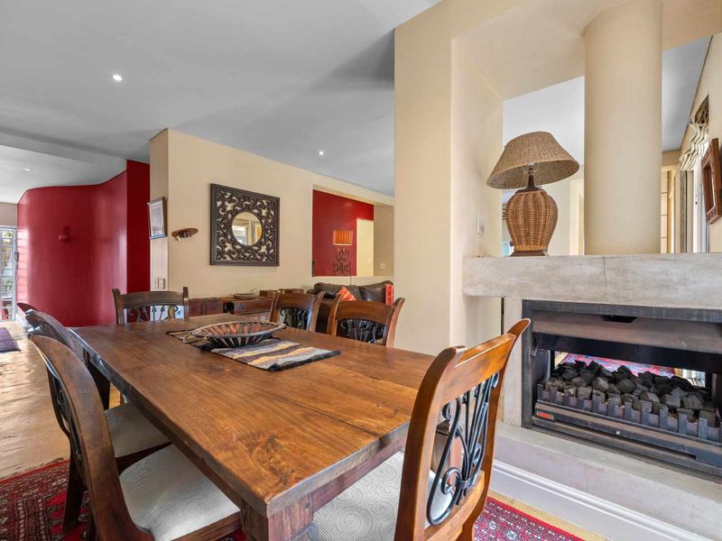 Dining area featuring hardwood flooring, recessed lighting, and a built-in fireplace with a structural column, creating a warm and inviting atmosphere.