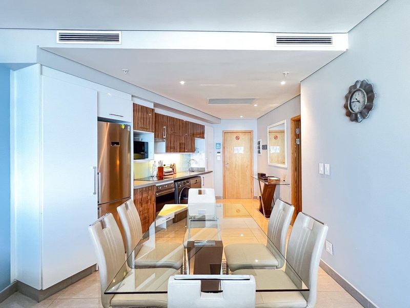 Modern open-plan kitchen and dining area featuring sleek cabinetry, integrated appliances, ducted air conditioning, and polished tiled flooring.