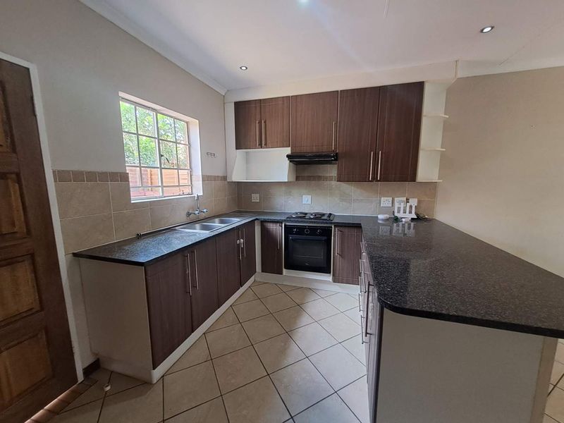 A functional kitchen featuring dark wood cabinetry, granite countertops, a built-in oven with gas hob, and a convenient breakfast nook.