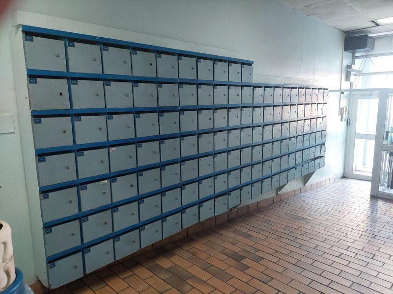 A communal apartment building entrance lobby featuring a large wall-mounted bank of individual mailboxes and durable tiled flooring.