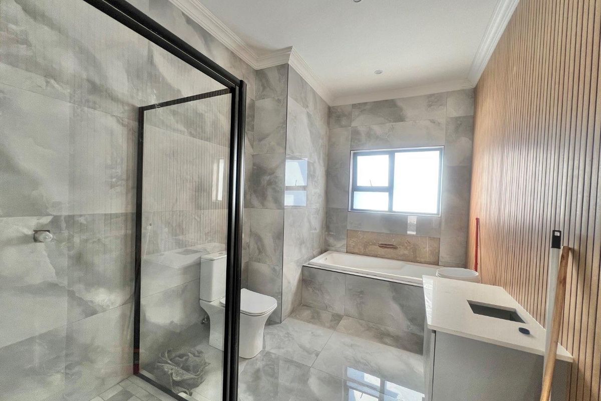 Modern bathroom featuring a glass-enclosed shower, a built-in bathtub, a vanity, and contemporary grey marble-style wall and floor tiling with wood-slat accent wall.