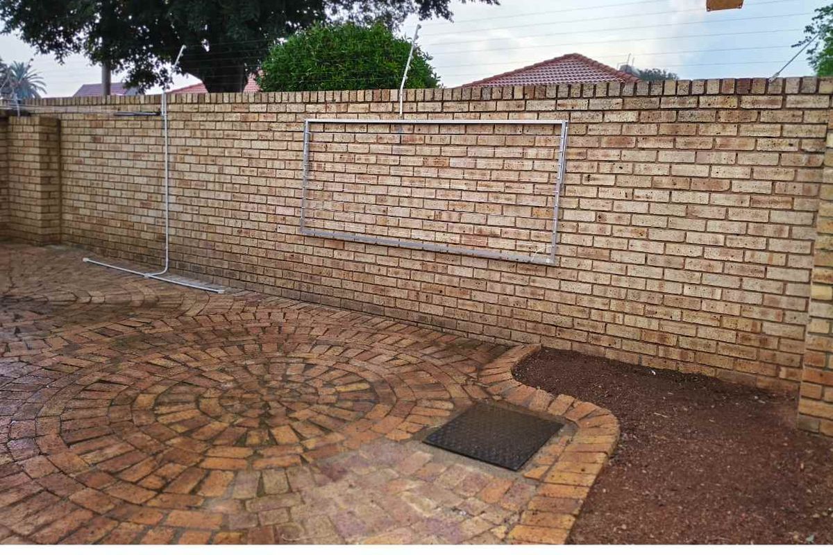 A private rear courtyard featuring face-brick boundary walls, paved flooring, and an integrated wall-mounted washing line structure.