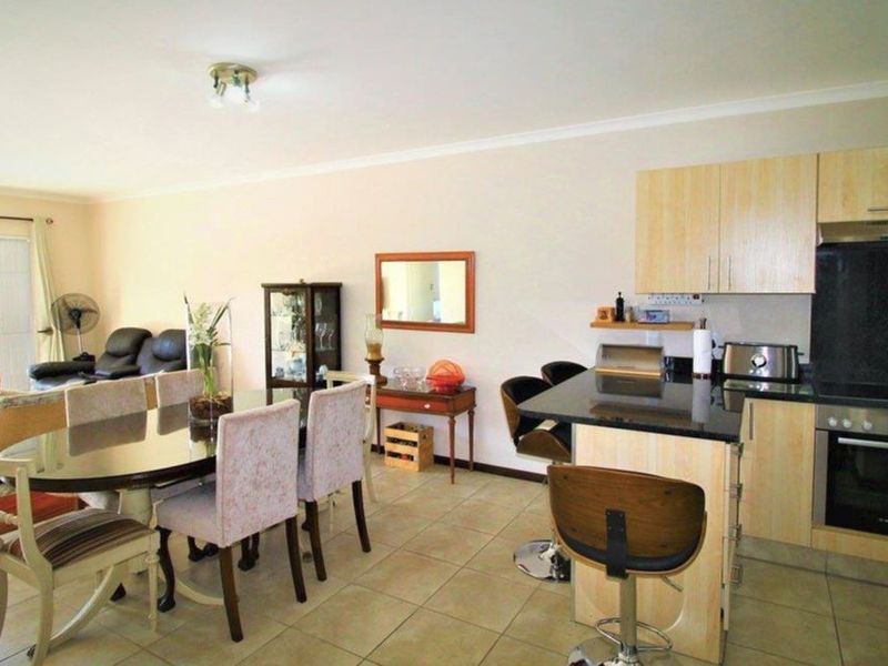 Open-plan living and dining area featuring a functional kitchen with granite countertops, built-in cabinetry, and direct access to a patio through sliding doors.