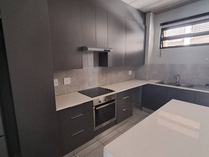 Modern kitchen featuring dark cabinetry, stone countertops, integrated appliances, and an industrial-style exposed concrete ceiling with tiled flooring.