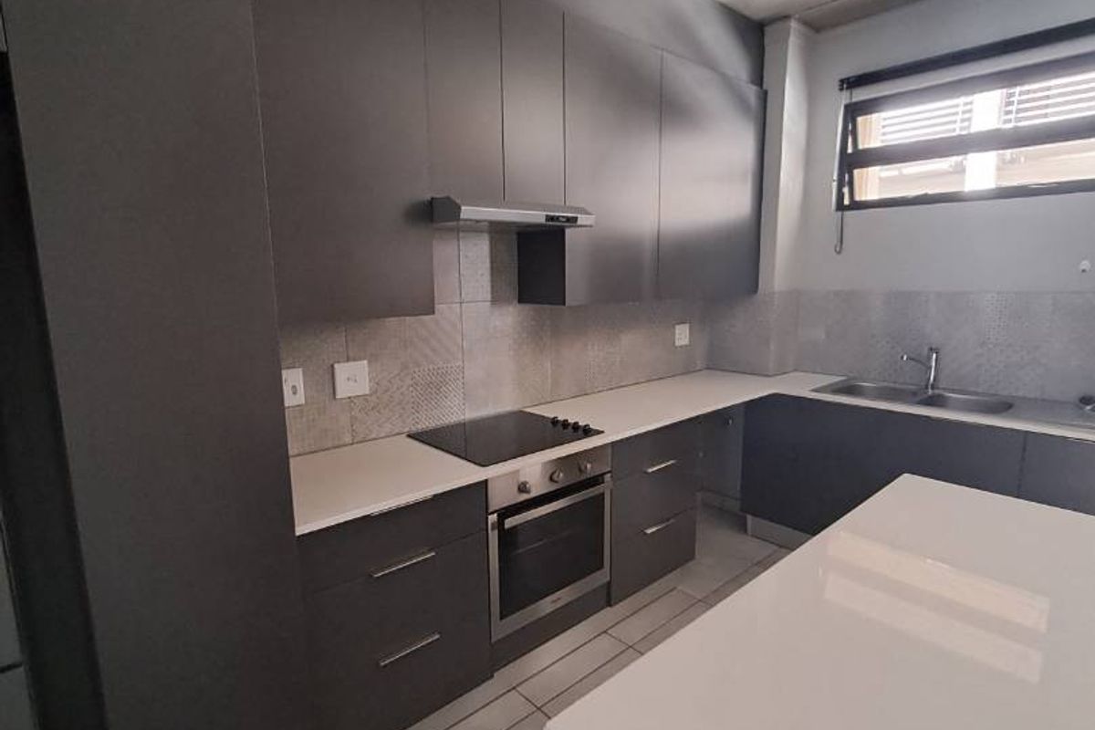 Modern kitchen featuring dark cabinetry, stone countertops, integrated appliances, and an industrial-style exposed concrete ceiling with tiled flooring.