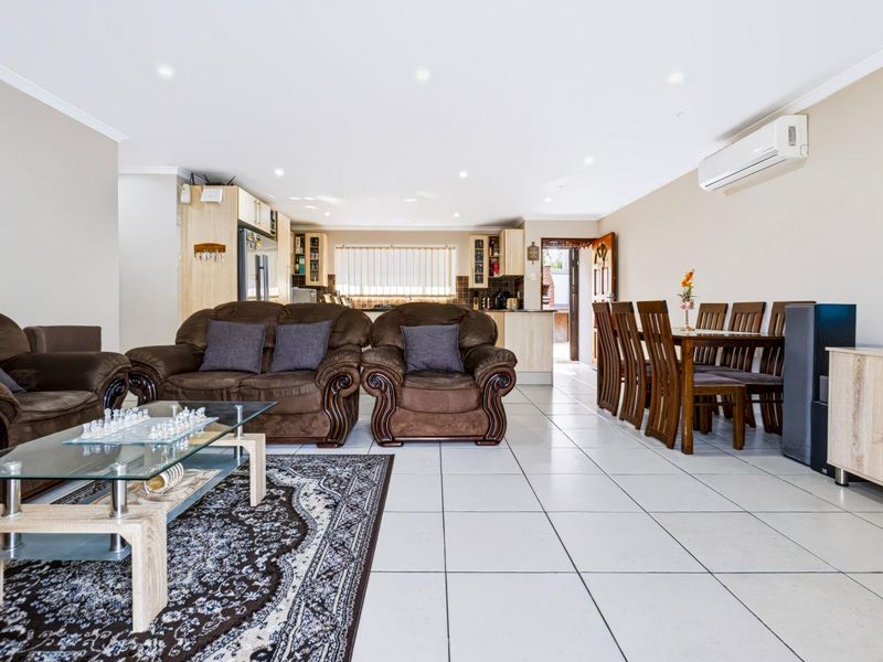 Spacious open-plan living and dining area featuring tiled flooring, recessed lighting, and a split-system air conditioner, seamlessly connected to the kitchen.