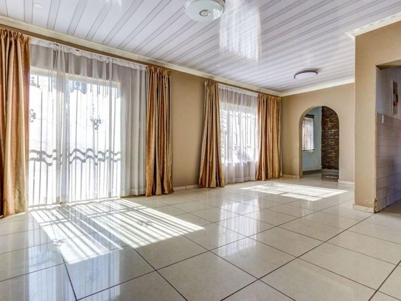 Spacious, light-filled living area featuring neutral tiled flooring, an arched entryway, and sliding glass doors leading to the exterior.