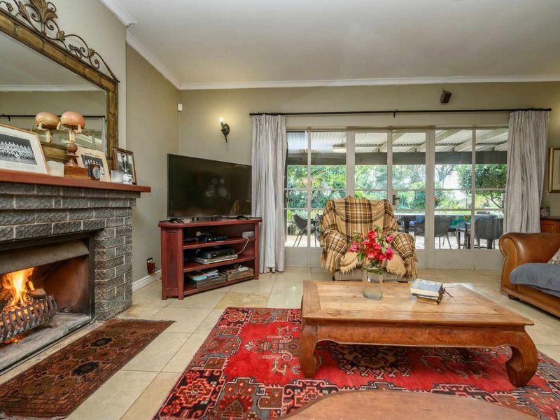 Cozy living room featuring a brick fireplace, tiled flooring, and large glass sliding doors providing natural light and access to the outdoor patio area.