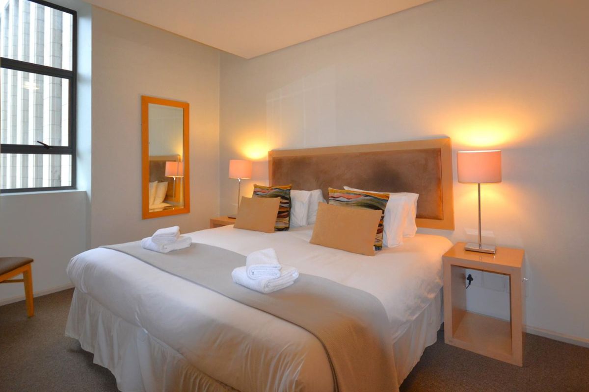 A well-maintained bedroom featuring neutral wall tones, carpeted flooring, and a large window providing natural light.