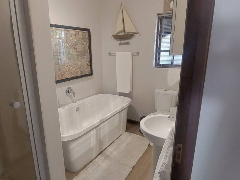 A well-maintained bathroom featuring a freestanding bathtub, pedestal basin, toilet, and a separate shower enclosure with glass door.