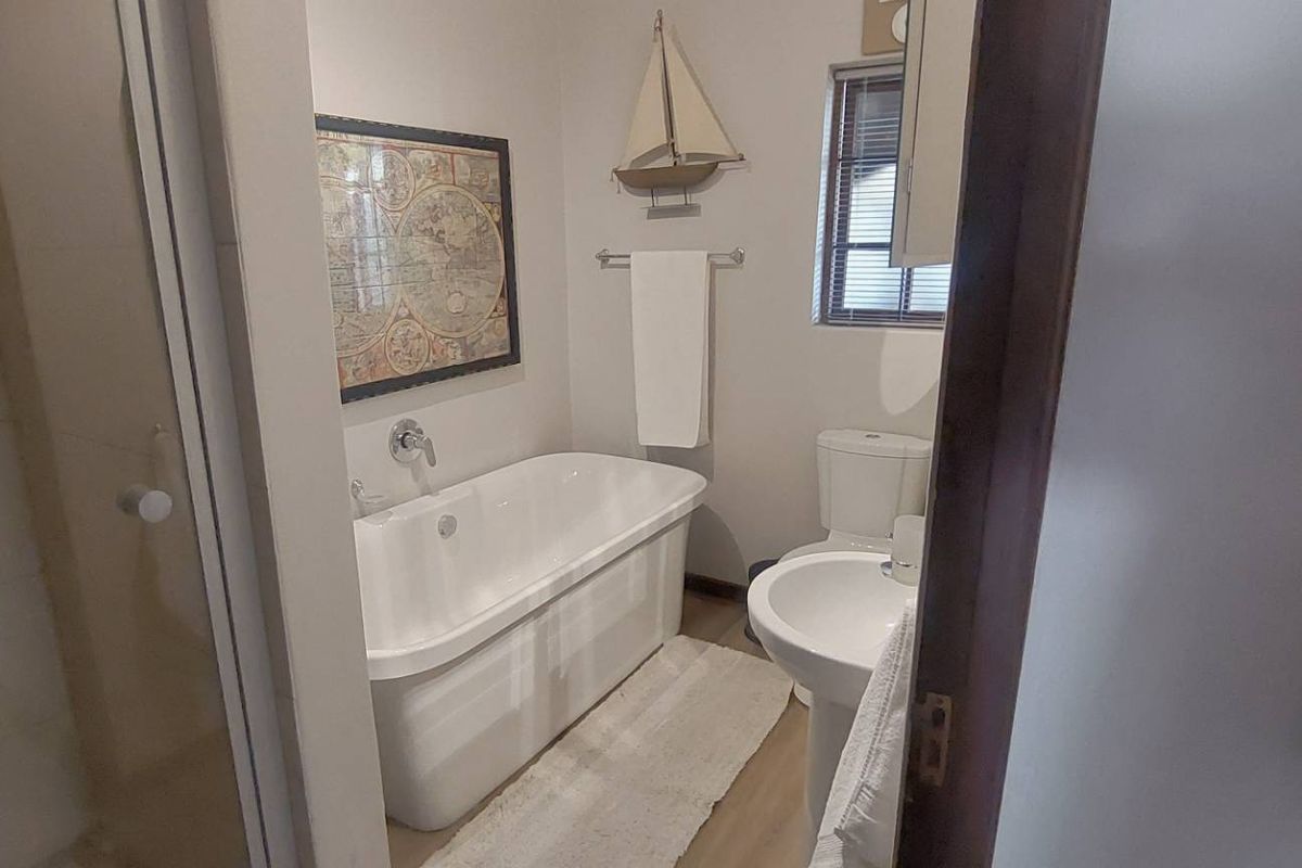 A well-maintained bathroom featuring a freestanding bathtub, pedestal basin, toilet, and a separate shower enclosure with glass door.