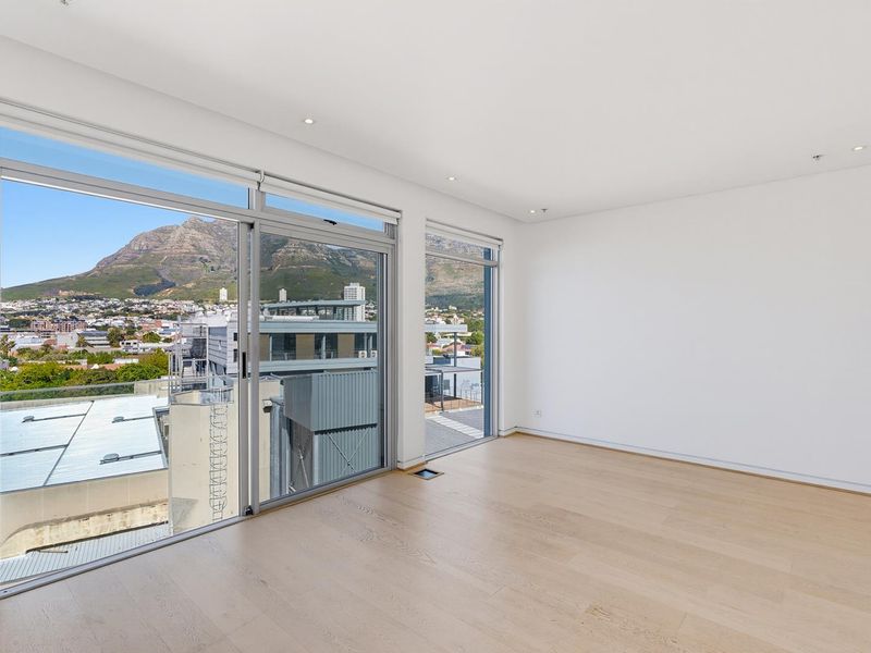 Bright and spacious living area featuring light timber flooring, recessed lighting, and large sliding glass doors offering expansive mountain and city views.