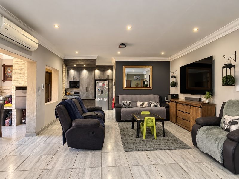 Spacious open-plan living area featuring tiled flooring, recessed lighting, air conditioning, and a modern kitchen with built-in cabinetry and an adjacent indoor braai area.