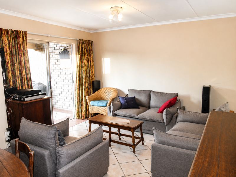 A comfortable living room featuring tiled flooring and a large sliding glass door that provides access to an outdoor patio area.