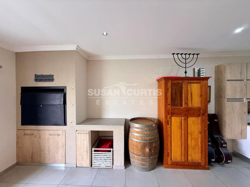 Covered patio area featuring a built-in braai, tiled flooring, and recessed ceiling lighting.