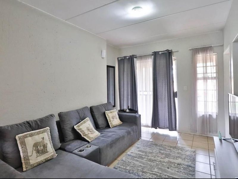 A functional living room featuring tiled flooring and a sliding glass door providing access to the exterior.