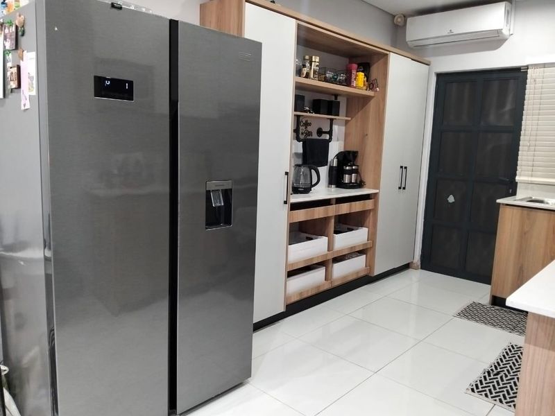 Modern kitchen featuring sleek built-in cabinetry, light wood accents, tiled flooring, and an integrated air conditioning unit.
