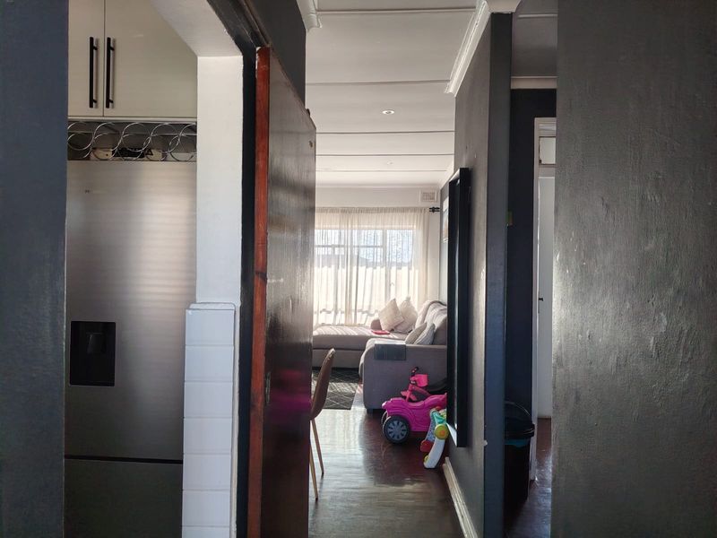 A view from the hallway looking into the living area, featuring dark painted walls, recessed ceiling lighting, and built-in kitchen cabinetry.