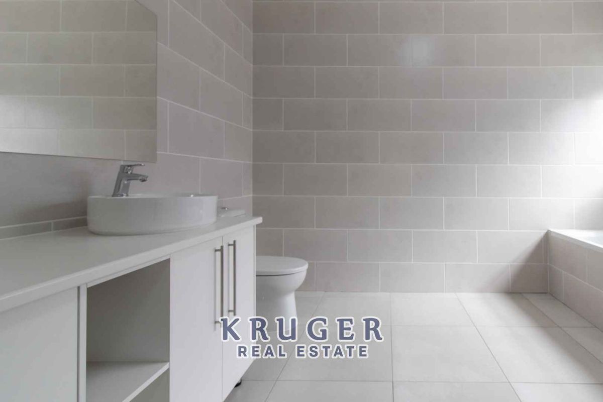 Modern bathroom featuring neutral wall tiles, a white vanity with a vessel sink, and a built-in bathtub.