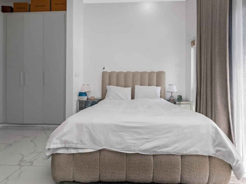 A well-maintained bedroom featuring built-in cupboards, modern marble-look floor tiles, and direct access to an outdoor area through a sliding glass door.