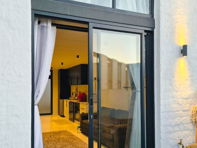 A view from a patio area looking into an open-plan living and kitchen space through a large sliding glass door.