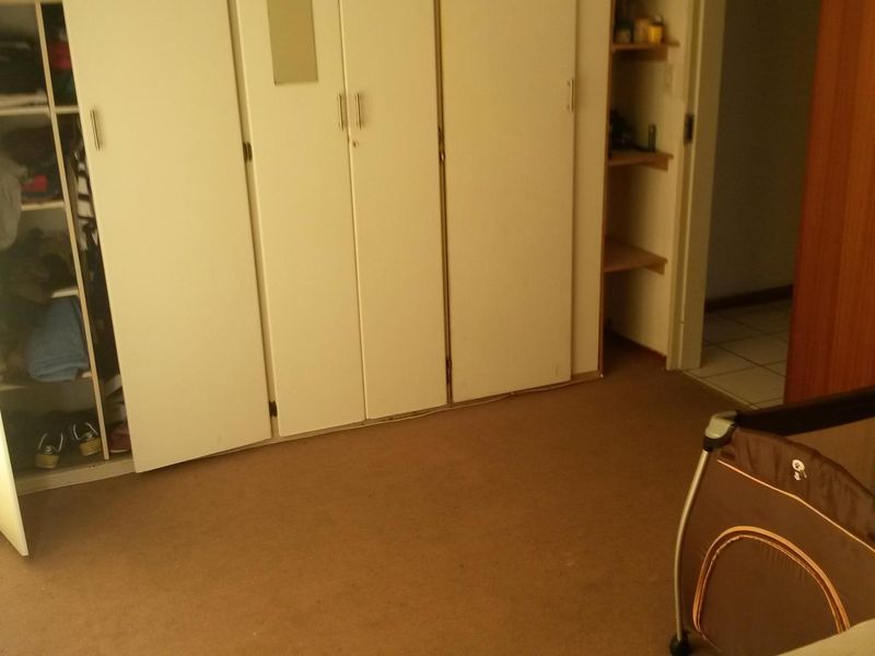 A bedroom featuring built-in cupboards and carpeted flooring, requiring cosmetic updates to improve the overall aesthetic and condition of the space.