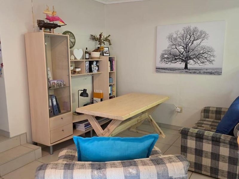 A living area featuring neutral tiled flooring and coved ceilings, providing a functional space with potential for modern updates.