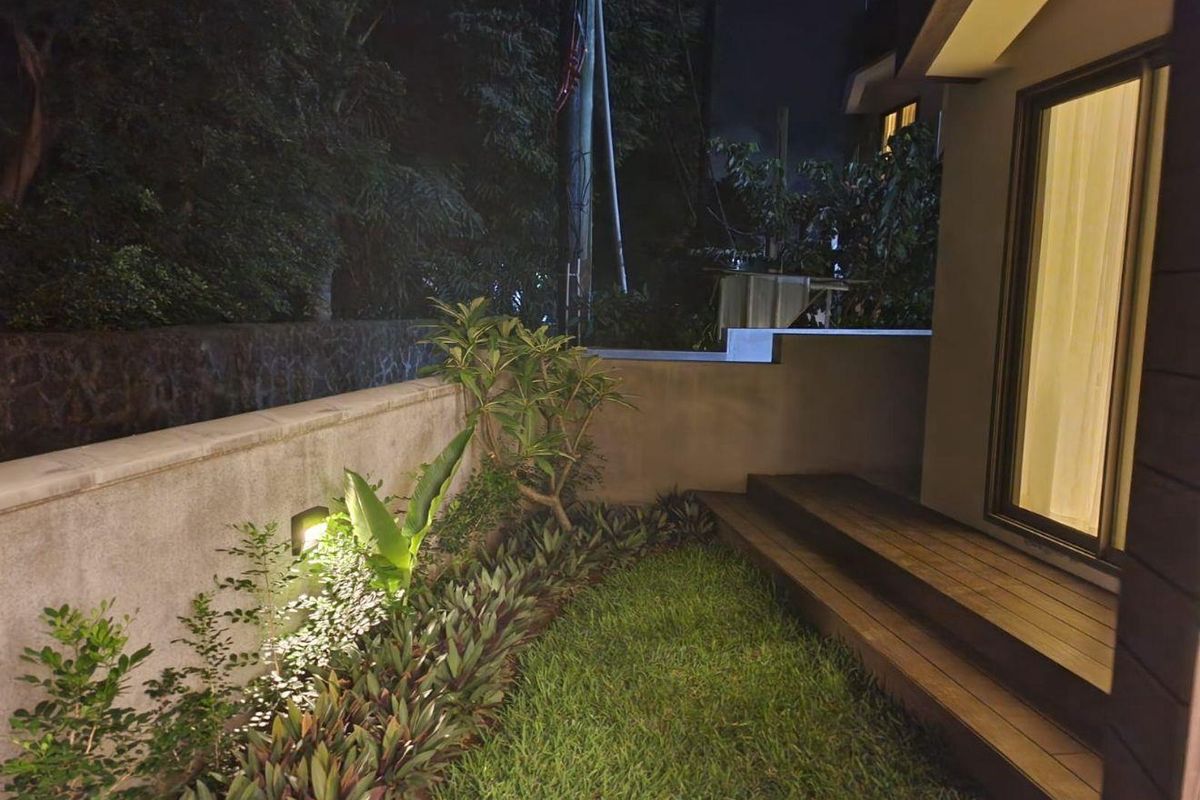 A well-maintained private garden area featuring a timber deck, landscaped garden beds, and integrated wall lighting, providing a pleasant outdoor space.