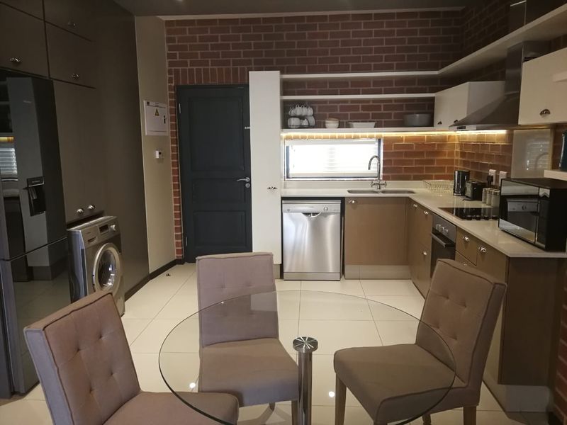 Modern kitchen featuring exposed brick walls, sleek cabinetry, integrated appliances, and under-cabinet lighting, creating a stylish and functional culinary space.