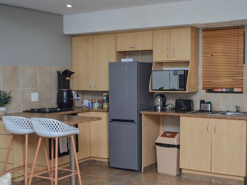 A functional kitchen featuring light wood-tone cabinetry, laminate countertops, tiled backsplash, and integrated appliances, offering a practical layout for daily use.