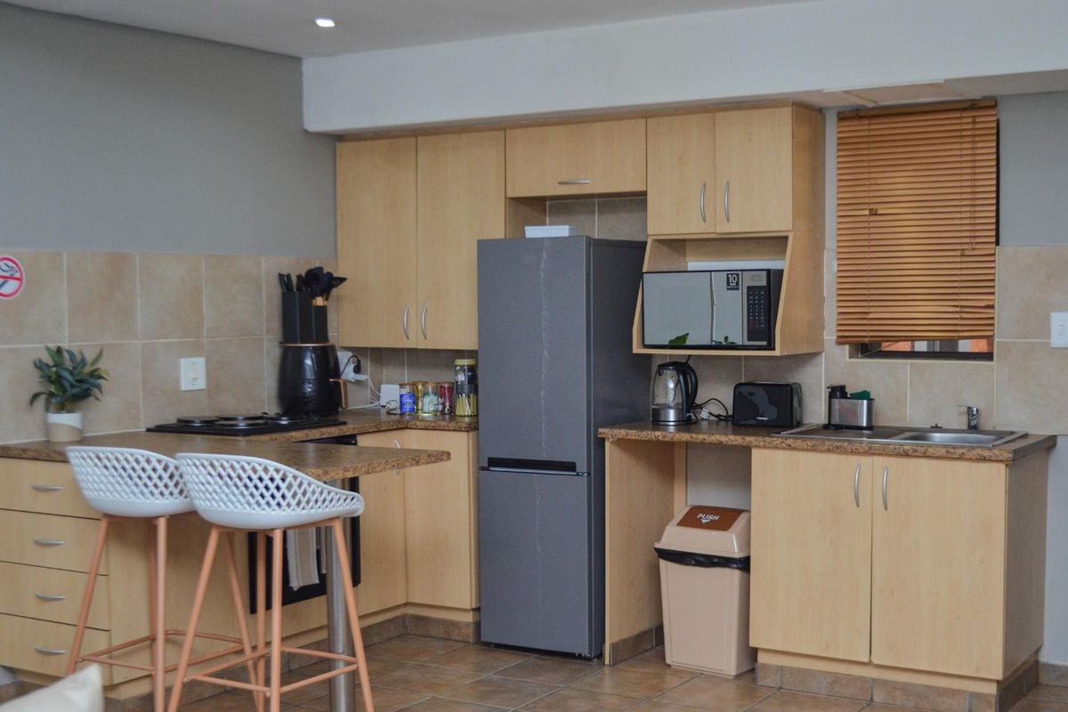 A functional kitchen featuring light wood-tone cabinetry, laminate countertops, tiled backsplash, and integrated appliances, offering a practical layout for daily use.