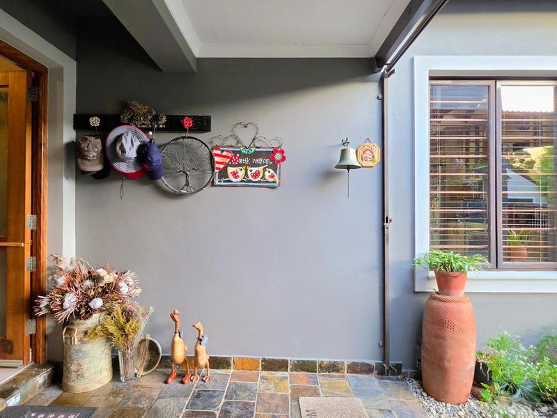 A covered patio area featuring slate tile flooring, a timber frame door, and a window with security bars.